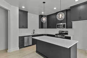 Kitchen featuring appliances with stainless steel finishes, dark cabinets, pendant lighting, light countertops, and recessed lighting