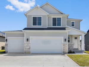 Craftsman house featuring stone siding, driveway, a front lawn, and an attached garage