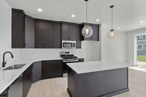 Kitchen with appliances with stainless steel finishes, light wood-type flooring, light countertops, and recessed lighting