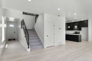 Foyer with recessed lighting, stairs, and light wood-type flooring