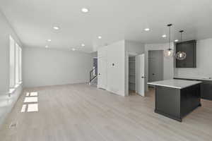 Kitchen with a center island, recessed lighting, light countertops, dark cabinetry, and light wood-style flooring
