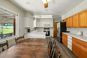 Kitchen with white appliances, dark wood-style flooring, light countertops, and white cabinets
