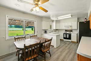 Kitchen with white appliances, white cabinets, healthy amount of natural light, and light countertops