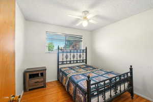 Bedroom featuring wood finished floors, a textured ceiling, and a ceiling fan