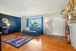 Living area with plenty of natural light, wood finished floors, and a textured ceiling