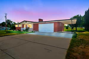 Single story home featuring a porch, a carport, concrete driveway, a yard, and an attached garage