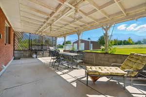 View of patio / terrace with outdoor dining area, a mountain view, an outdoor structure, a ceiling fan, and area for grilling