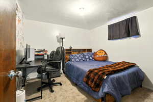 Carpeted bedroom featuring a desk and baseboards