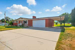 View of front of house with brick siding, a front yard, concrete driveway, a chimney, and a garage