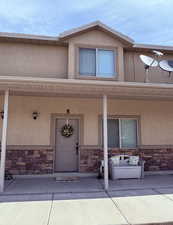 Doorway to property with stone siding, stucco siding, and a porch