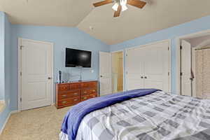 Bedroom with vaulted ceiling, carpet floors, a closet, and a ceiling fan