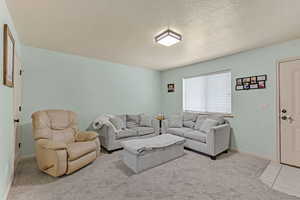 Living room featuring a textured ceiling, light colored carpet, and light tile patterned flooring