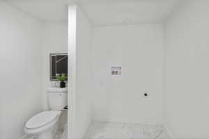 Bathroom featuring marble look tile flooring and toilet