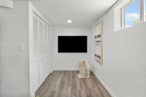 Hall featuring light wood-type flooring, a textured ceiling, and recessed lighting
