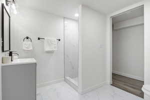 Full bath featuring marble look tile flooring, vanity, and walk in shower