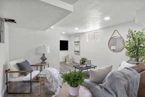 Living room with wood finished floors, a textured ceiling, and recessed lighting