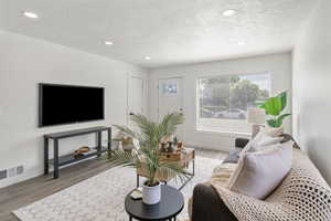 Living area with a textured ceiling, wood finished floors, plenty of natural light, and recessed lighting