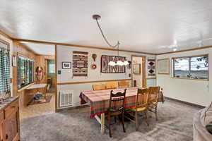 Dining room featuring carpet floors, wooden walls, a textured ceiling, and crown molding