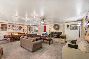 Living room with light colored carpet, a ceiling fan, crown molding, a wood stove, and rail lighting