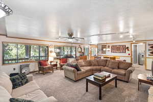 Carpeted living area featuring water heater and ceiling fan