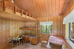 Bunkhouse featuring wood walls, wooden ceiling, and vaulted ceiling