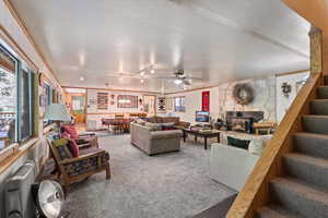 Living room with stairs, carpet flooring, plenty of natural light, and ceiling fan