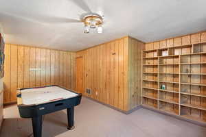 Game room featuring wood walls, a textured ceiling, and carpet floors