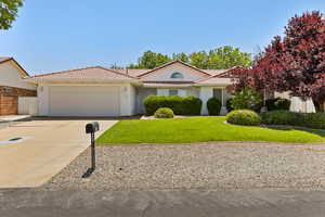 Mediterranean / spanish house with an attached garage, a tiled roof, concrete driveway, and stucco siding