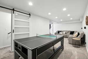 Recreation room with a barn door, light carpet, and recessed lighting