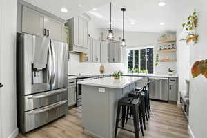 Kitchen featuring stainless steel appliances, open shelves, quartz countertops, and a center island