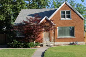 View of front of house featuring brick  and a shingled roof.