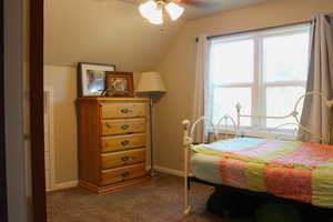 Carpeted bedroom with vaulted ceiling and a ceiling fan