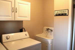 Washroom featuring cabinet space and washing machine and dryer and cool old sink
