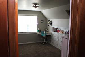 Bedroom featuring lofted ceiling and dark carpet