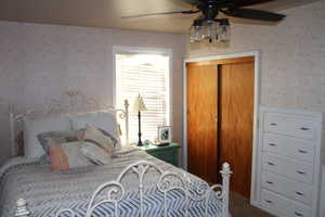 Carpeted bedroom featuring built in drawers, ceiling fan, and a closet