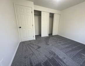 Unfurnished bedroom featuring dark carpet and a closet