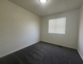 Empty room featuring dark carpet
