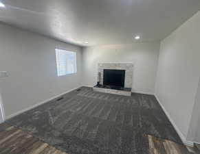 Unfurnished living room featuring a stone fireplace, recessed lighting, wood finished floors, and carpet floors