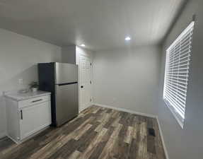 Kitchen with freestanding refrigerator, dark wood-type flooring, recessed lighting, light countertops, and white cabinetry