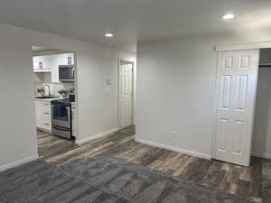 Kitchen with appliances with stainless steel finishes, dark wood-type flooring, recessed lighting, and white cabinets
