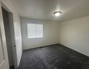 Unfurnished room featuring dark carpet