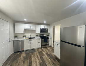 Kitchen featuring stainless steel appliances, recessed lighting, dark wood finished floors, white cabinets, and light stone counters