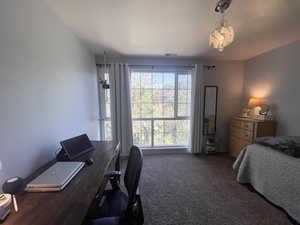 Carpeted bedroom featuring an office area and a chandelier