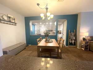 Carpeted dining room with a chandelier and baseboards