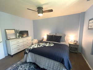 Bedroom with dark carpet and a ceiling fan