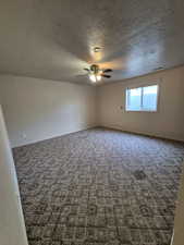Carpeted spare room featuring ceiling fan and a textured ceiling