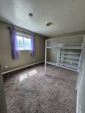 Unfurnished bedroom with carpet floors and a textured ceiling