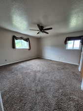 Spare room with carpet flooring, plenty of natural light, a ceiling fan, and a textured ceiling