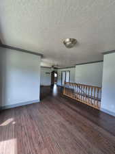 Unfurnished room with a ceiling fan, hardwood / wood-style floors, a textured ceiling, and crown molding