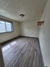 Unfurnished room with wood finished floors and a textured ceiling